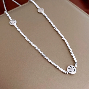 Macro shot of silver cube beads and smiley face pendants on a metallic choker necklace