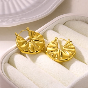 Close-up of golden irregular fold texture earrings on white velvet jewelry box
