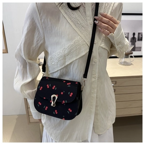 Detail der schwarzen Satteltasche mit Kirschprint und goldener Hufeisenschnalle am Model