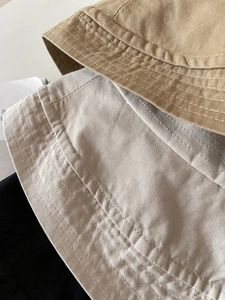 Close-up of cotton twill bucket hats in khaki and beige showing fine stitching texture