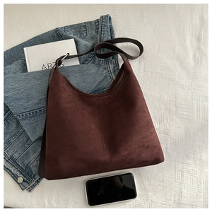 Detailed texture of a dark brown velvet hobo bag on denim with artsy lifestyle props