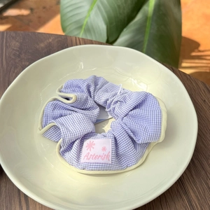 Close-up of lilac striped fabric scrunchie with Asterisk label in a ceramic tray