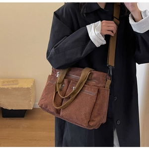 Detail of a brown corduroy crossbody bag featuring multiple zipper pockets and texture