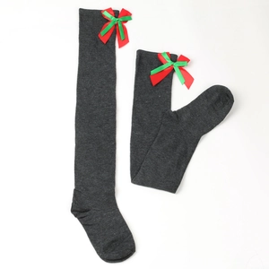 Detailed knit texture of dark grey over-the-knee socks with festive red and green bows