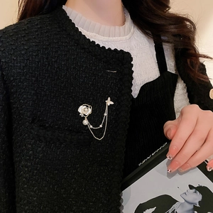 Détail de la broche fleur et papillon avec chaînes de perles sur veste en tweed