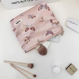 Detailed embroidery of colorful butterflies on a pink silk shoulder bag with makeup items