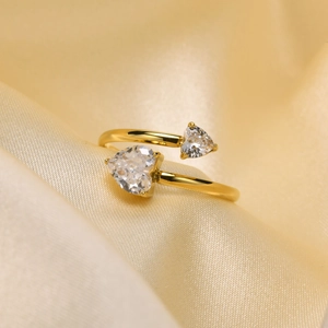 Close-up of gold-plated heart ring with clear cubic zirconia on champagne satin background