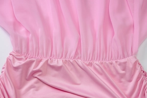 Detailed macro view of pink chiffon pleats and smooth knit fabric stitching on the dress