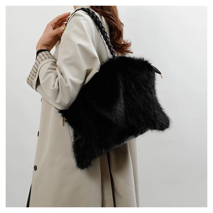 Close-up of black fuzzy plush shoulder bag with woven leather strap and gold zipper detail