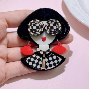 Detail of acrylic girl brooch with pop art design held against a soft pink background
