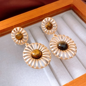 Detailed macro view of vintage hollow metal earrings with inlaid brown tiger eye stone