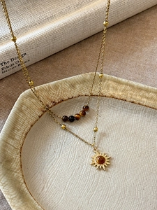 Close-up of double-layered sun necklace with tiger eye beads on a ceramic plate