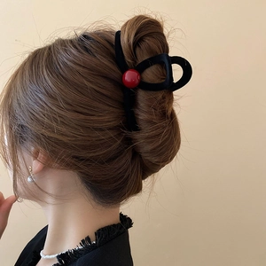 Detail of elegant black flocked hair claw with a red bead accent on model hair
