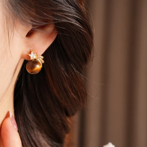Détail d'une boucle d'oreille étoile avec pierre œil de tigre et zircon sur l'oreille