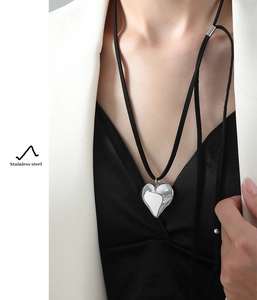 Close-up of heart-shaped stainless steel pendant necklace on black suede cord with model