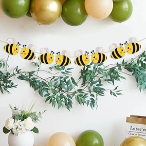 Cute yellow bee party banner decoration with balloons and green plants on white wall