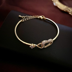 Macro view of gold-plated bracelet with pavé zircon heart charms on black leather surface