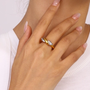 Gros plan d'une bague croisée bicolore en or et argent sur la main d'un mannequin