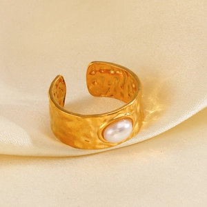 Golden hammered texture wide band ring with inlaid pearl on beige silk background