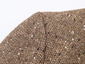 Gros plan du tissu en tweed à chevrons marron avec détails de texture tissée multicolore