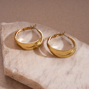 Close-up of golden double-layer hoop earrings with metallic finish on white stone