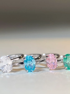 Macro view of oval-cut zircon rings in blue, pink, and green with silver bands