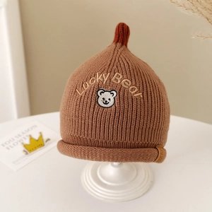 Detail of knitted baby hat featuring brown ribbed texture and Lucky Bear embroidery