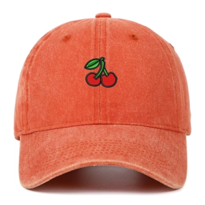 Close-up of cherry embroidery and vintage washed cotton texture on an orange baseball cap