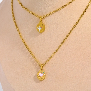 Detail of gold double-layer necklace featuring hand-painted pigeon and pink heart charms