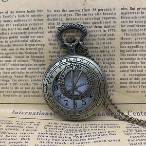 Vintage bronze pocket watch with Roman numerals on an antique newspaper background