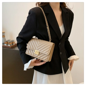 Close-up of beige quilted leather chain bag with golden square buckle and V-shaped stitching