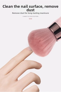 Detail of soft pink nail dust brush removing powder from fingernails with rose gold handle