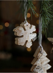 Close-up of rustic birch bark snowflake and tree ornaments with warm bokeh lights