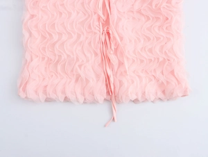 Détail du haut rose à col en V montrant la texture gaufrée 3D et les lacets