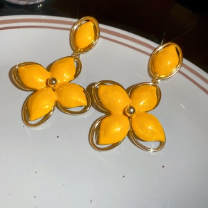 Gros plan de boucles d'oreilles fleurs jaunes émaillées avec bordure dorée sur plat