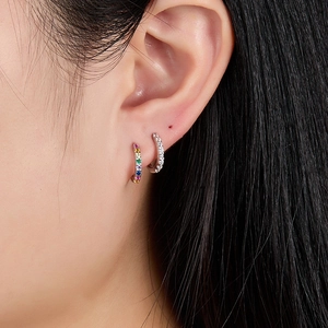 Close-up of model wearing stylish rainbow and white zircon hoop earrings in minimalist style