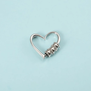 Detail of silver heart-shaped earring with textured beads on a light blue background