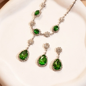 Détail macro du collier avec pendentif goutte émeraude et boucles d'oreilles argentées