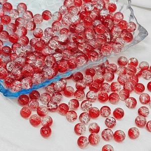Macro shot of 6mm red cracked glass beads for DIY jewelry making on white fabric