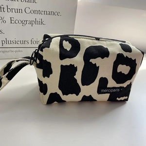 Detalle del estuche de lona con estampado de vaca, cremallera y etiqueta merciparis lateral