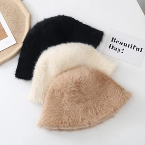 Flat lay of fuzzy rabbit fur bucket hats in black, beige, and khaki on white background