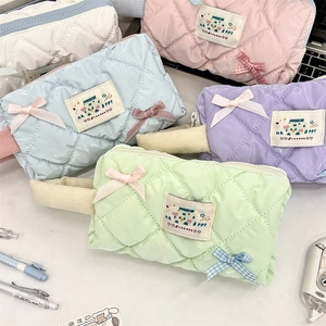 Flat lay of five quilted pearlescent pencil cases in pastel colors with ribbon bows