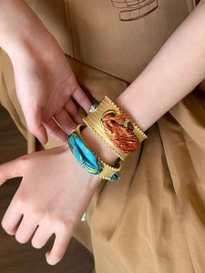 Vintage gold cuff bracelet with silk floral print and woven metal texture on a model wrist