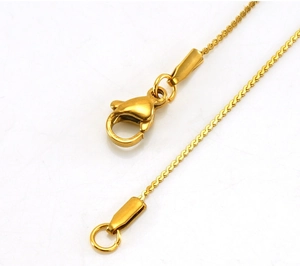 Detail of 18K gold stainless steel chain featuring a lobster clasp and polished wave links