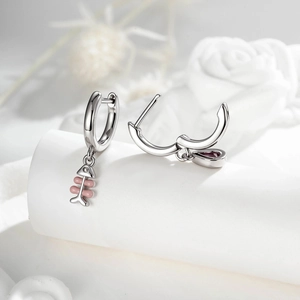 Asymmetric earrings featuring pink fishbone and purple teardrop pendants on silver hoops