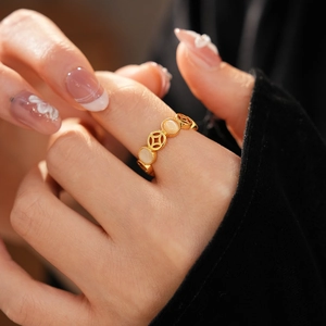 Détail macro d'une bague dorée style monnaie avec résine opale sur un doigt