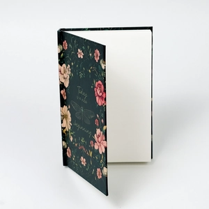 Detailed view of hardcover notebook with dark green floral cover and plain white paper