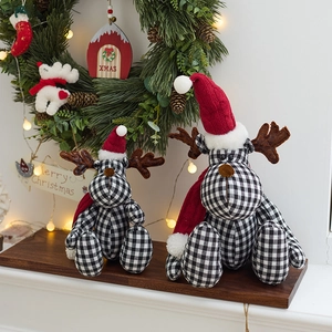 Christmas reindeer plush figurines in black and white plaid with red hats on festive background