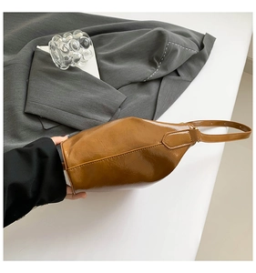 Close-up of brown polished oil-wax leather shoulder bag with adjustable strap and side view