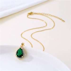 Elegant gold chain necklace with emerald teardrop pendant surrounded by small zircons